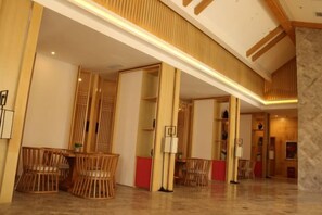 Een hotel lobby met houten meubilair, een marmeren kolom en een hoge plafond.