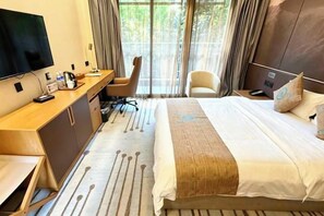 Ett hotellrum med en säng, ett skrivbord, en stol och en tv.