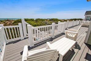 Une terrasse en bois avec des rampes blanches, un banc et une table.
