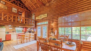 A rustic cabin with a wooden interior, a dining area with wooden chairs, a kitchen with a red refrigerator, and a sign indicating 'Joe Lee's Market'.