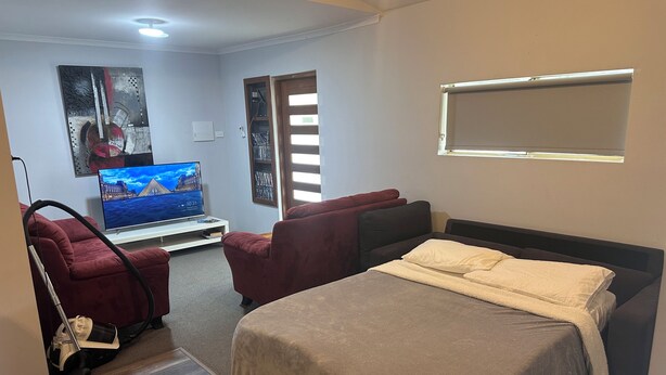 A bedroom with a bed, a TV, a vacuum cleaner, and a bookshelf. - Quaint Flat, near hospitals, Very central, internet (Geraldton)