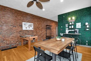 Ein Essbereich mit einem Holztisch und Stühlen, einer Ziegelwand, einer Weltkarte und einer grünen Wand mit Kaffee-Accessoires.