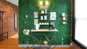 A coffee and tea bar with a green wall, a bicycle, and various coffee-making equipment.