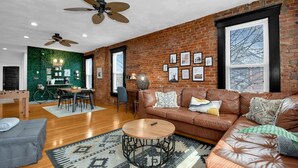 A spacious living room with a leather sofa, a coffee table, and a green wall.