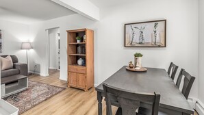 A modern living room with a dark wooden dining table, a wooden cabinet, and a floor lamp. - Bright & Spacious 2 Bedroom | Quiet | Safe | Clean (Mount Clemens)