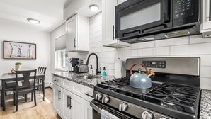 A modern kitchen with white cabinets, a stainless steel stove, a black microwave, and a granite countertop. - Bright & Spacious 2 Bedroom | Quiet | Safe | Clean (Mount Clemens)