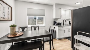 A modern kitchen with white cabinets, a black refrigerator, and a dining area with a table and chairs. - Bright & Spacious 2 Bedroom | Quiet | Safe | Clean (Mount Clemens)