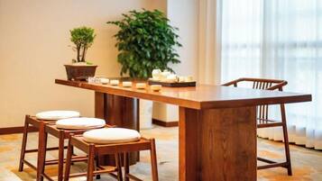 A wooden dining table with four chairs, a potted plant, and candles on the table.