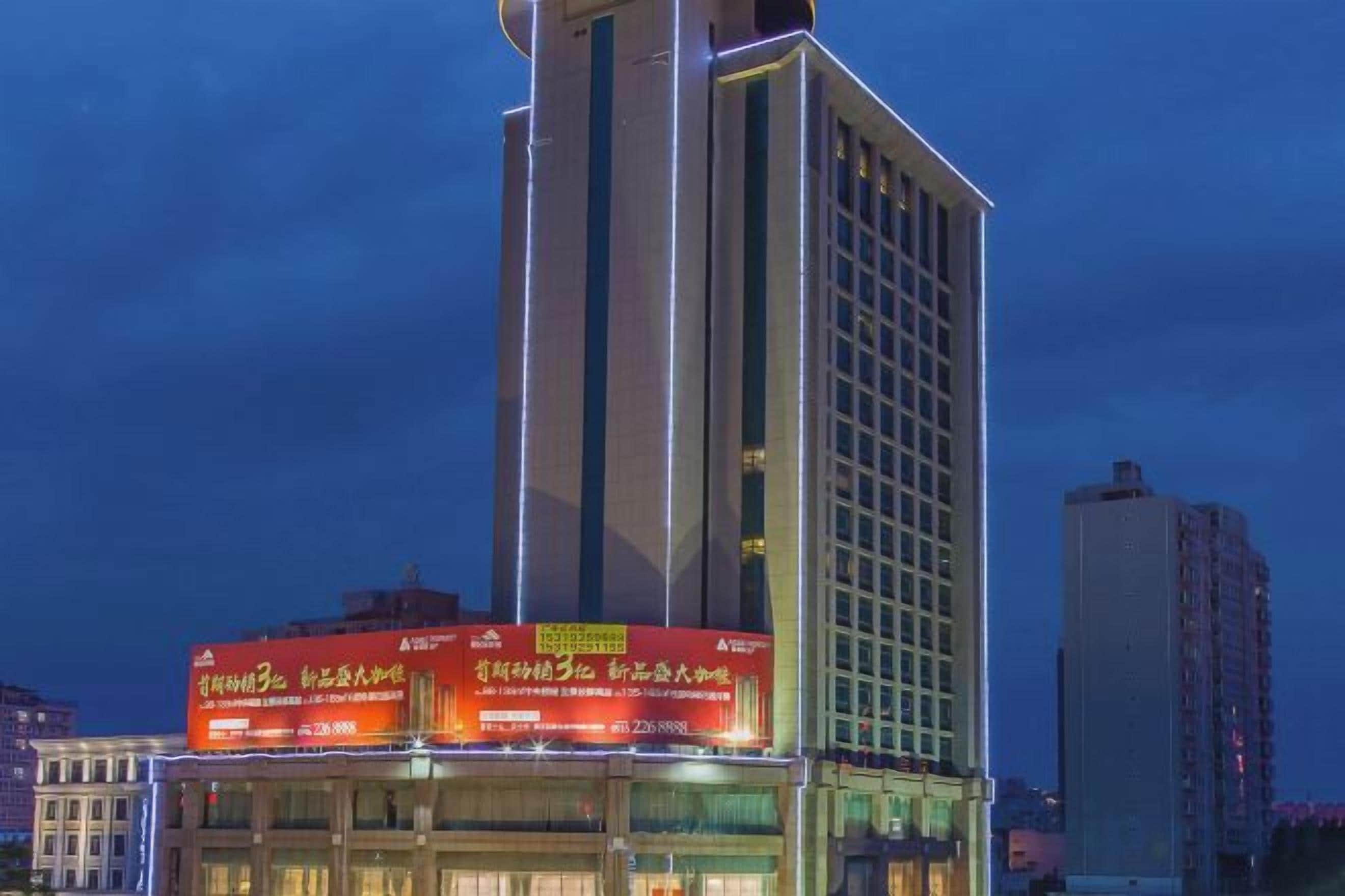 Un edificio alto con señalización iluminada en la parte superior.