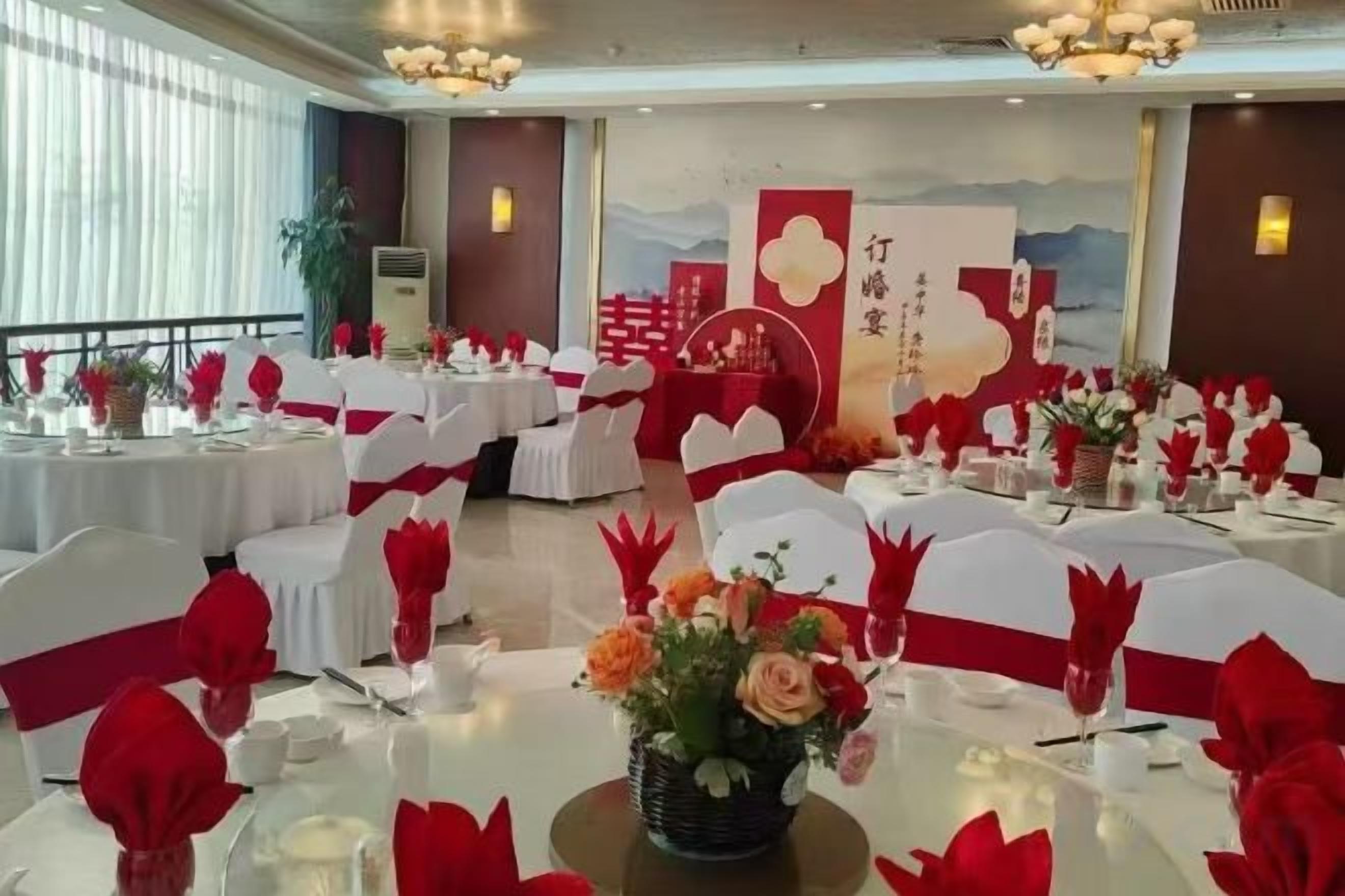 A banquet hall with round tables, white tablecloths, and red sashes.