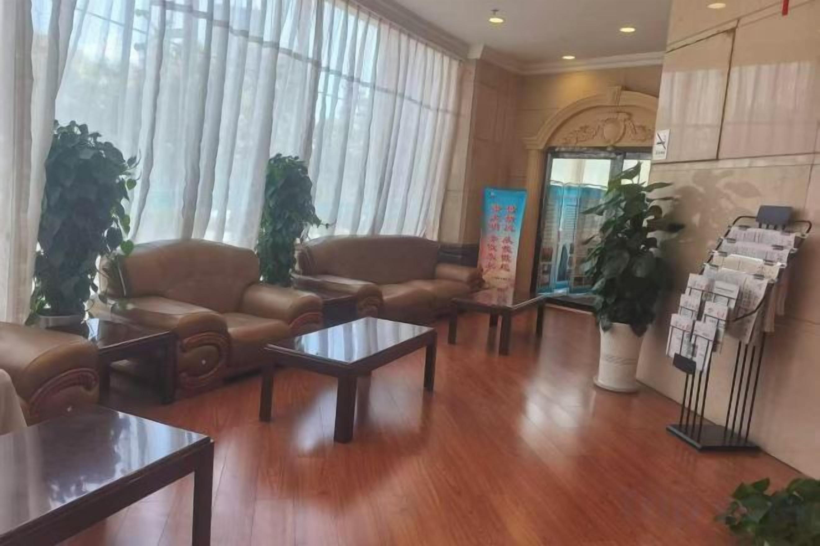 A lobby with leather sofas, a reception desk, and a plant stand.