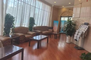 A lobby with leather sofas, a reception desk, and a plant stand.