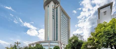 A hotel with a prominent cylindrical tower, a modern facade, and a clear sky.