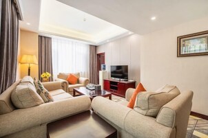Una habitación de hotel con un conjunto de sofás, un televisor, una lámpara y un cuadro en la pared.