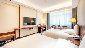 Habitación de hotel con dos camas, televisión, escritorio y una silla.