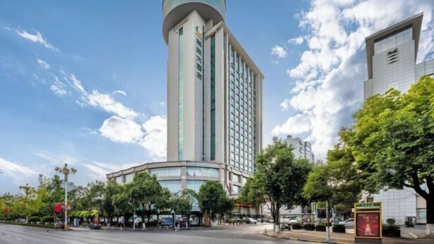 Un hotel alto con un extremo cilíndrico, una construcción con esquina curva y un moderno revestimiento de vidrio.