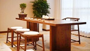 Una mesa de madera para comer con cuatro sillas, una planta en maceta y velas sobre la mesa.