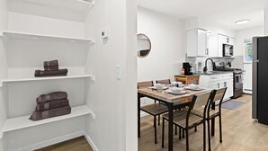 Een moderne keuken met witte kasten, een eettafel en een zwarte koelkast.