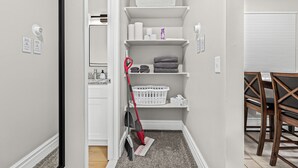 A laundry room with shelves for towels and laundry supplies, a mop, and a laundry basket. - Prime Location! King Bed near Mt. Clemens Downtown (Mount Clemens)