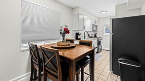 A modern kitchen with white cabinets, a black refrigerator, and a dining area with a wooden table and chairs. - Prime Location! King Bed near Mt. Clemens Downtown (Mount Clemens)