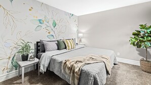 A bedroom with a bed, bedside table, lamp, and a potted plant. - Prime Location! King Bed near Mt. Clemens Downtown (Mount Clemens)