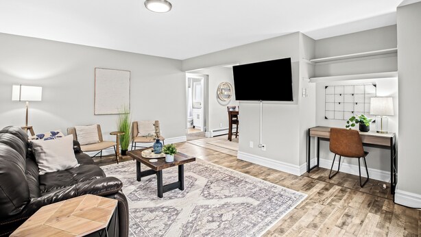 A modern living room with a leather sofa, a coffee table, and a desk area with a chair. - Prime Location! King Bed near Mt. Clemens Downtown (Mount Clemens)