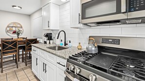 A modern kitchen with white cabinets, a stainless steel stove, a microwave, and a granite countertop. - Prime Location! King Bed near Mt. Clemens Downtown (Mount Clemens)