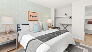 A bedroom with a bed, nightstands, a desk, and a shelving unit. - Contemporary 1BR, Fast WiFi, Pet-Friendly (Mount Clemens)