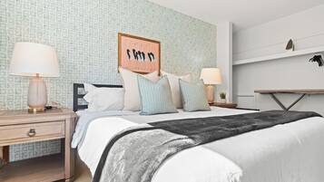 A neatly arranged bedroom with a bed, bedside tables, and a wall-mounted shelf.