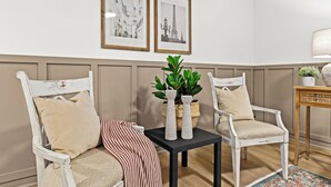 A room with two white chairs, a black table, and two framed pictures on the wall. - Cozy Modern 1BR Close to Downtown (Mount Clemens)