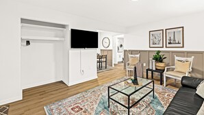 A modern living room with a sofa, coffee table, and a TV mounted on the wall. - Cozy Modern 1BR Close to Downtown (Mount Clemens)