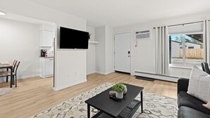 Una sala de estar moderna con una mesa de centro negra, un sofá y un televisor montado en la pared.