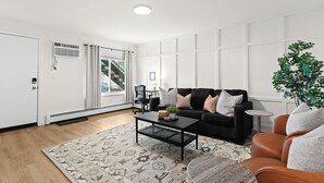 Una sala de estar moderna con un sofá negro, una mesa de centro y un tapete estampado.