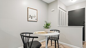 A dining area with a round table, two black chairs, a potted plant, and a framed artwork on the wall. - Quiet Cozy End Unit Near Mt. Clemens Downtown (Mount Clemens)
