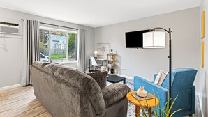 A modern living room with a grey sofa, a blue armchair, a small side table, and a floor lamp. - Quiet Cozy End Unit Near Mt. Clemens Downtown (Mount Clemens)
