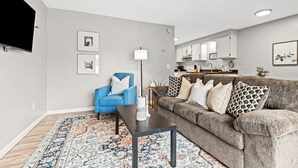 A modern living room with a grey sofa, a blue armchair, a coffee table, and a patterned rug. - Quiet Cozy End Unit Near Mt. Clemens Downtown (Mount Clemens)