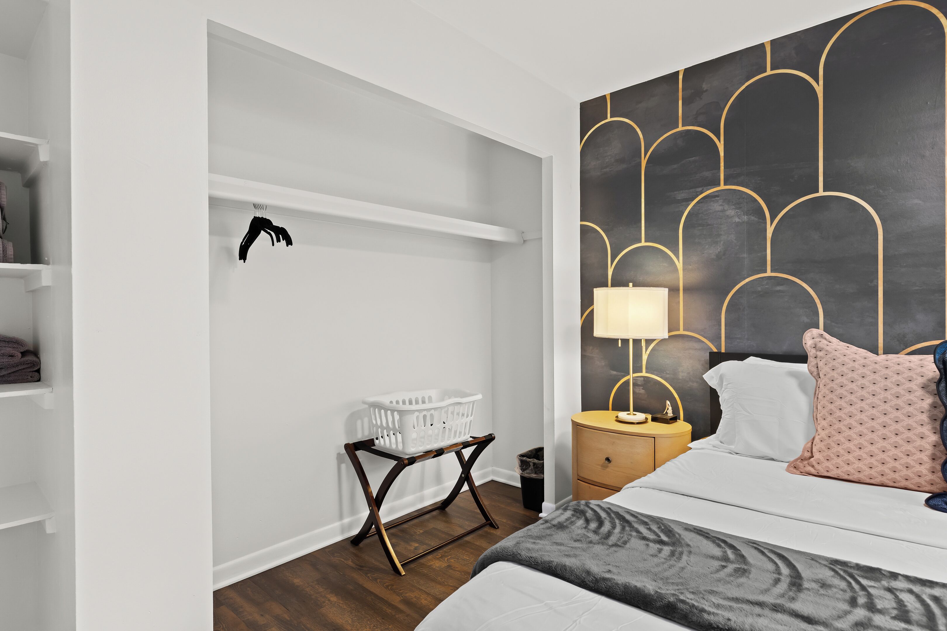 Une chambre à coucher comprenant un lit, une table de chevet, une lampe et un mur orné de motifs géométriques.