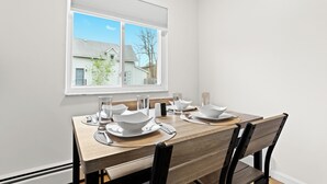 Een eethoek met een houten tafel gedekt voor vier personen, witte borden en zwarte stoelen.