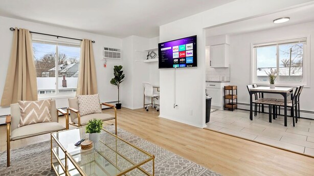 Una sala de estar moderna con una mesa de centro de vidrio, un sofá beige y un televisor de pantalla plana montado en la pared.