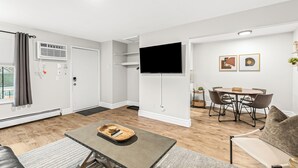 Una sala de estar moderna con televisor de pantalla plana, un comedor con mesa y sillas, y un rincón de descanso acogedor con sofá y mesa de centro.