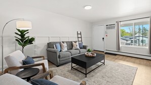 En moderne stue med en grå sofa, et sort sofabord og en gulvlampe.