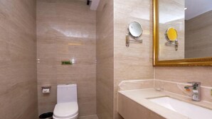 A bathroom with a toilet, sink, mirror, and a trash bin. - Vienna International Hotel Nanning Wuyi Fude (Nanning)