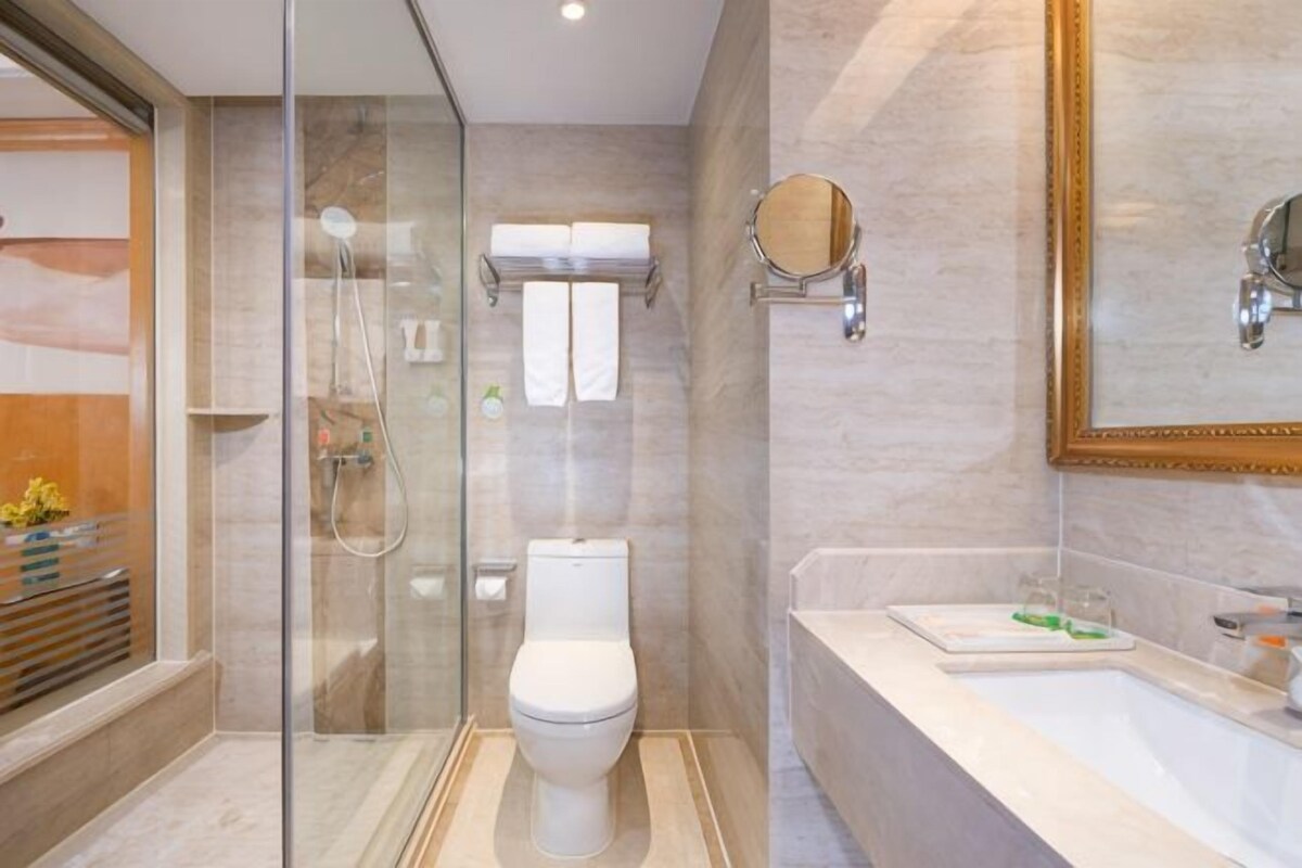 Un baño moderno con cabina de ducha de vidrio, inodoro, bañera y un espejo grande.