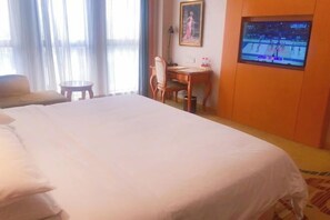 A hotel room with a large bed, a desk, a chair, a television, and a window with curtains. - Vienna International Hotel Nanning Wuyi Fude (Nanning)