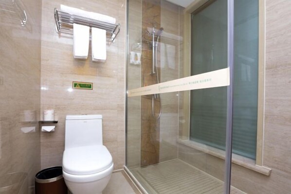 Et moderne badeværelse med et glasafskærmet brusebad, toilet og et håndklædetørrestativ.