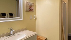 Ein Badezimmer mit Waschbecken, Spiegel und Duschvorhang.