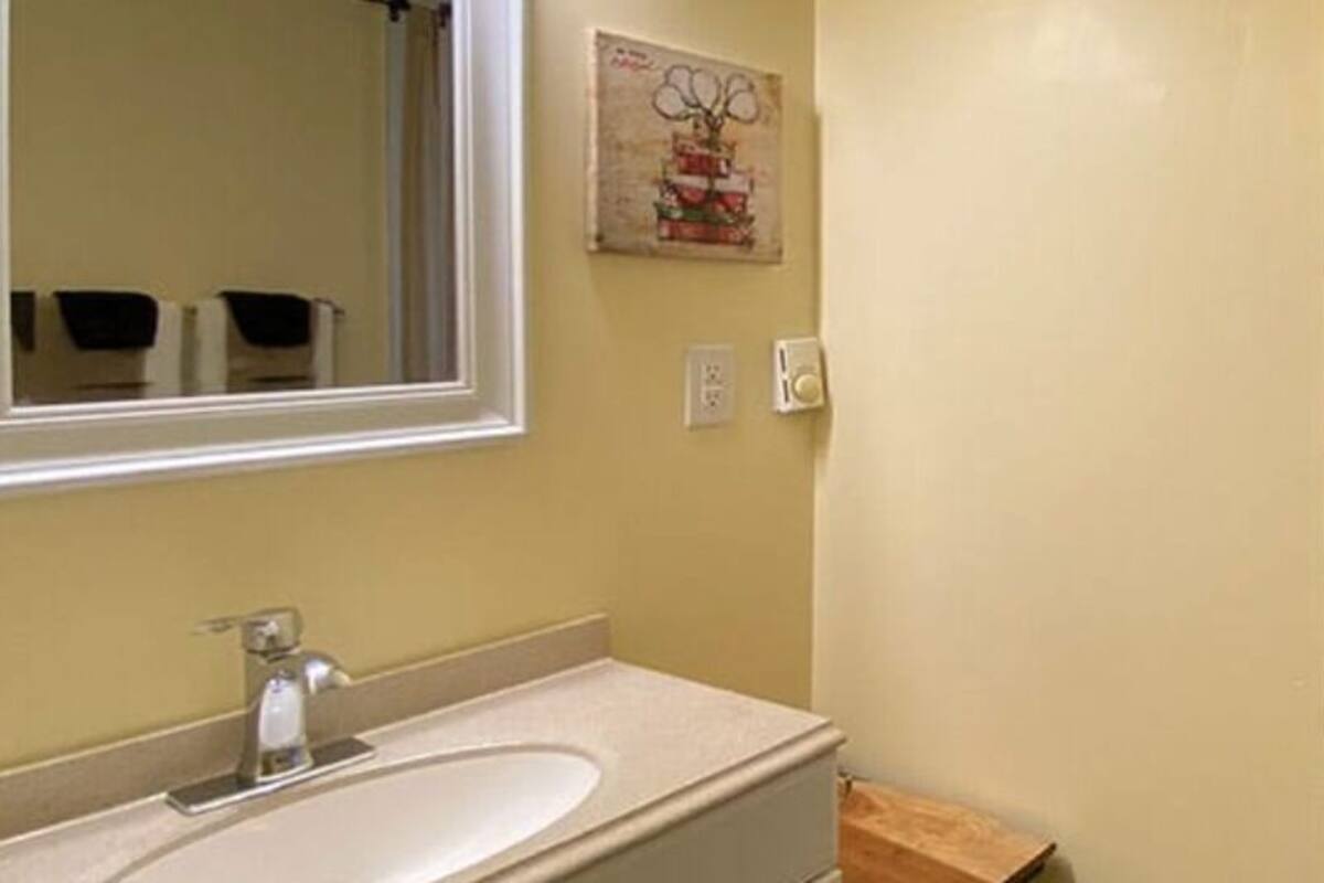 A bathroom with a sink, mirror, and shower curtain.
