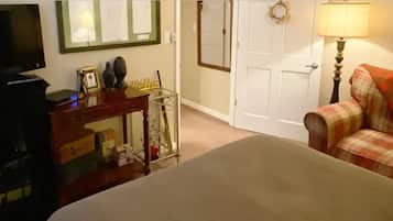 A bedroom with a bed, a dresser, a TV, and a door.