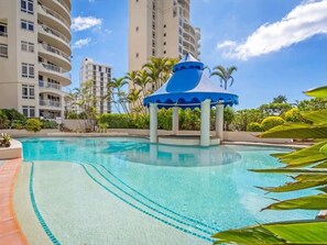 Relax by the pool surrounded by lush greenery and a gazebo.