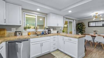A modern kitchen with white cabinets, a dishwasher, and a countertop with various appliances.